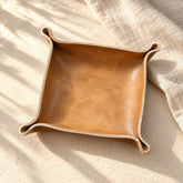 Plain tan leather valet tray with hand-formed corners on ivory linen