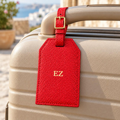 Personalised red luggage tag attached to a suitcase handle